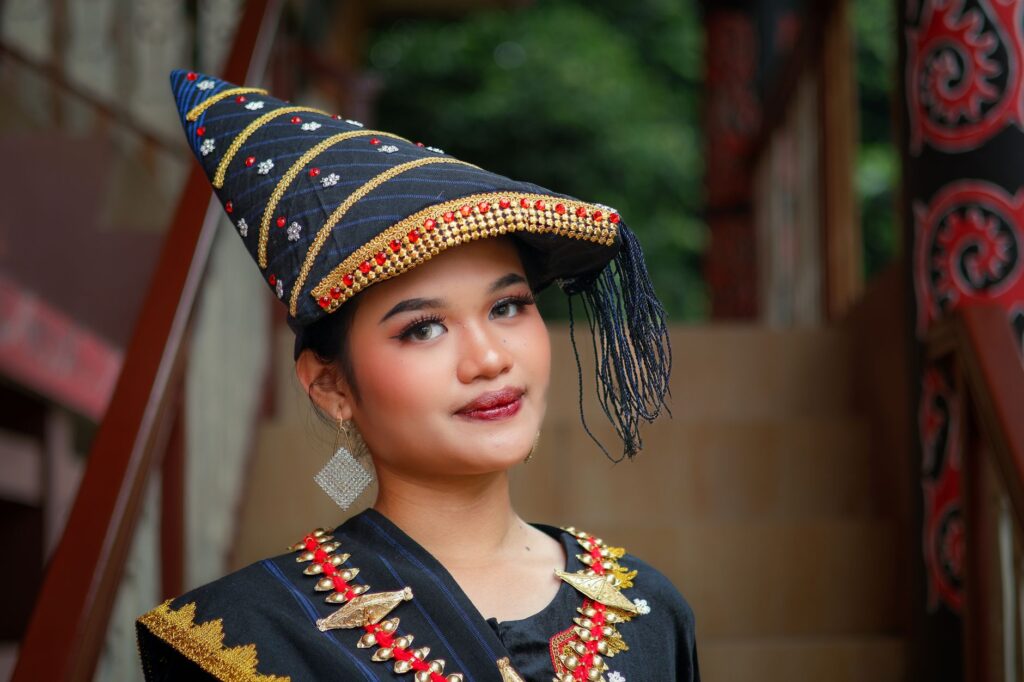 A woman in traditional attire with a decorated hat poses confidently.