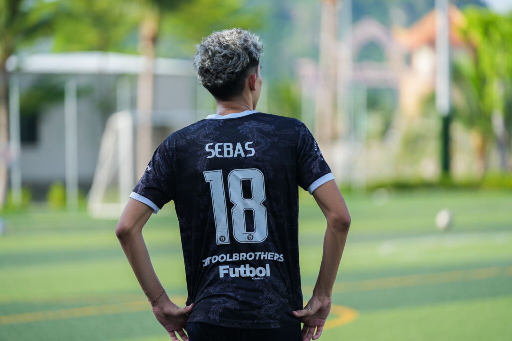 Back view of a soccer player wearing jersey number 18 on a sunny day outdoors.