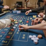 A lively casino scene with players placing bets and handling gaming chips on a roulette table.