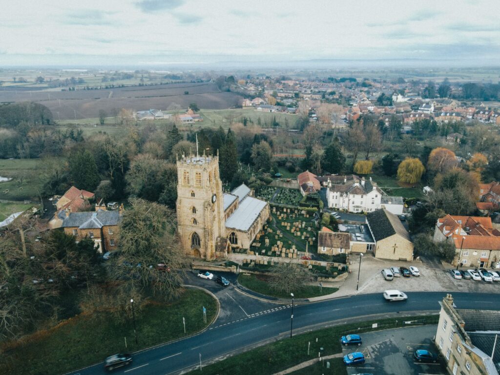 Explore a tranquil aerial view of a historic church and surrounding village, capturing the essence of rural architecture.