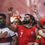 Excited group of soccer fans passionately cheering at a game, showing their vibrant team spirit.