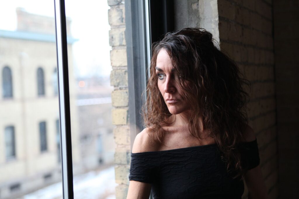 Portrait of a thoughtful woman gazing out a window in Minneapolis, capturing a serene and introspective moment.