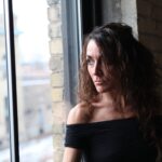 Portrait of a thoughtful woman gazing out a window in Minneapolis, capturing a serene and introspective moment.