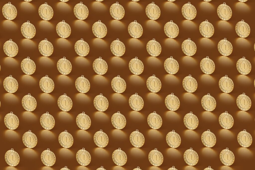 Multiple gold medals arranged in a repeating pattern on a brown backdrop.
