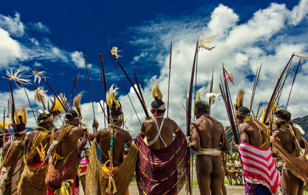 A group of indigenous men in traditional tribal clothing with bows and arrows during a cultural gathering in Papua, Indonesia.