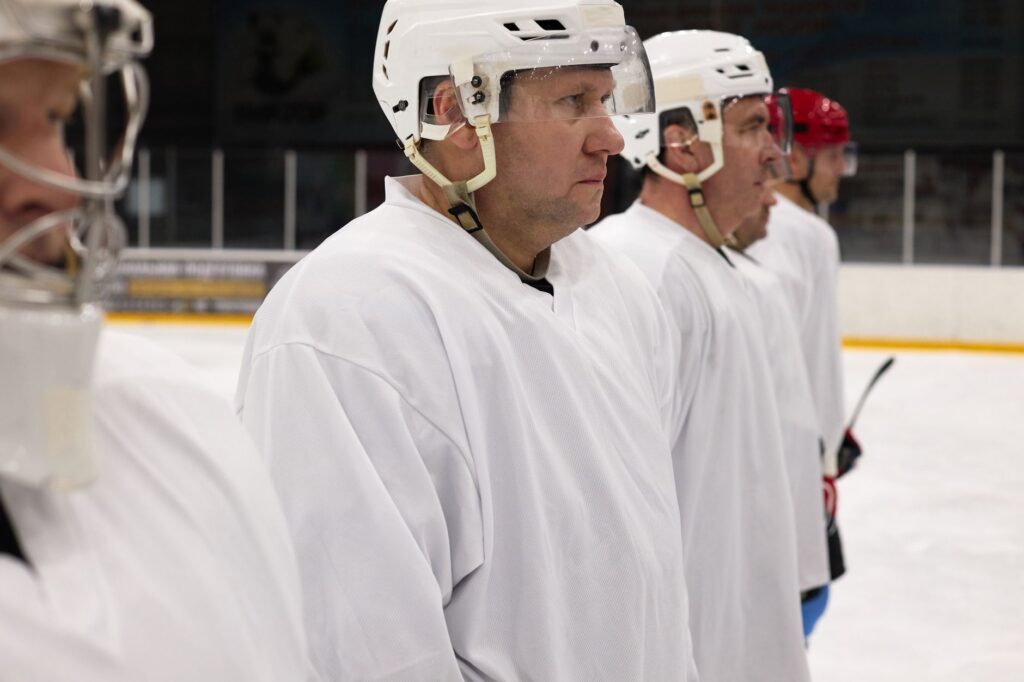 Ice hockey players in white uniforms line up on the rink, ready for action.