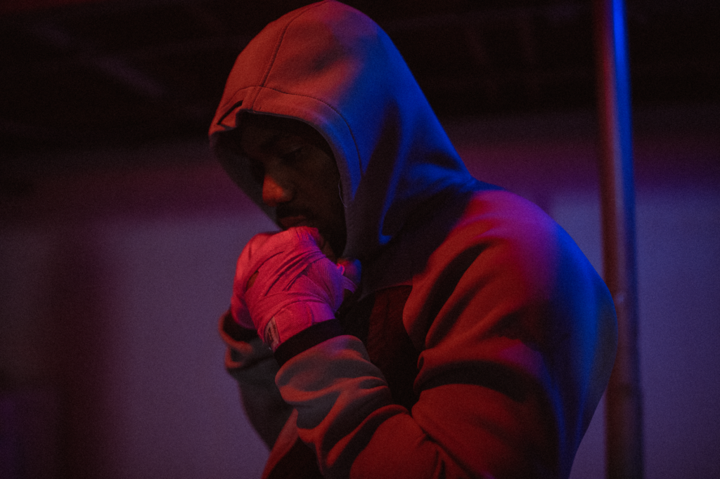A focused African American man in a hoodie prepares for training in an Ottawa boxing gym.