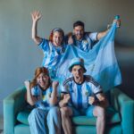 Group of fans celebrating Argentina's soccer victory at home, wearing team jerseys.
