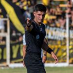 Soccer referee signaling a decision during an intense game outdoors.