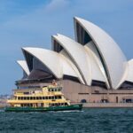 View of the Sydney Opera House with a ferry passing by in Sydney Harbour, Australia.