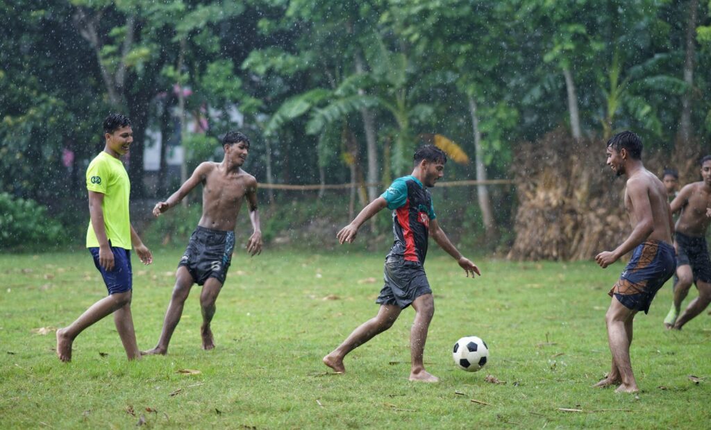 Vibrant and youthful soccer game in a rainy field in Jhenaidah, Bangladesh.