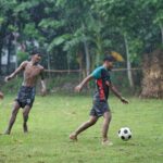 Vibrant and youthful soccer game in a rainy field in Jhenaidah, Bangladesh.