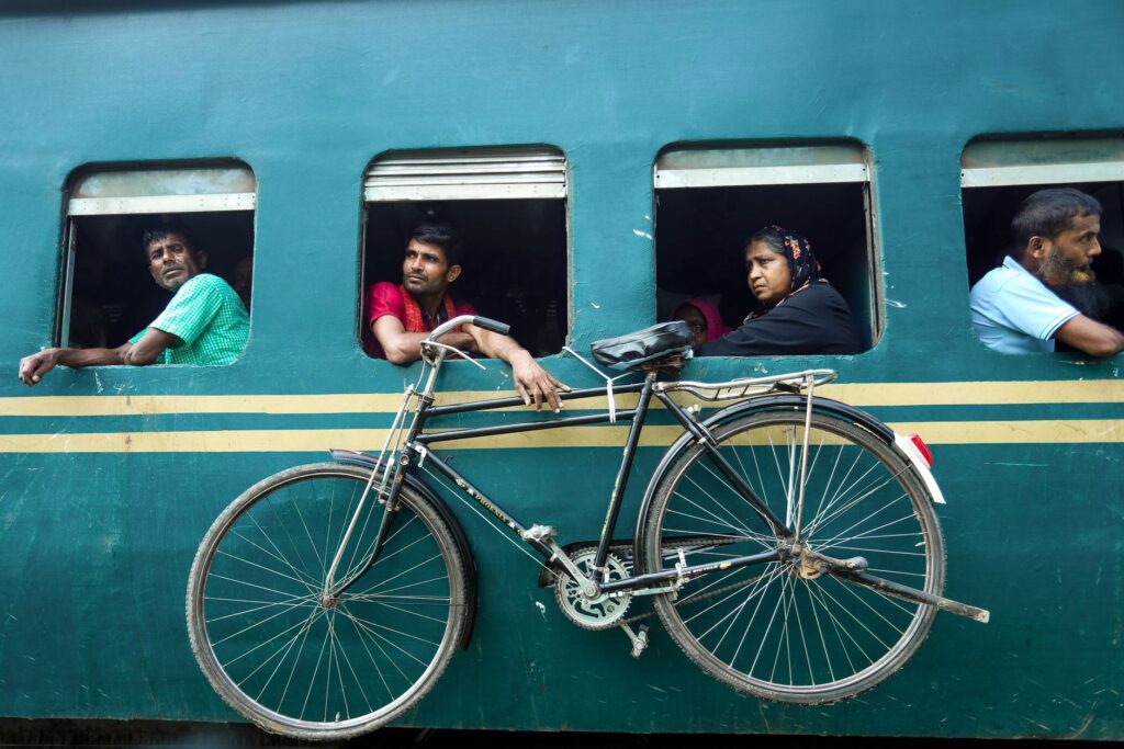Travelers on a train looking out the window with a bicycle attached, capturing daily life travel.