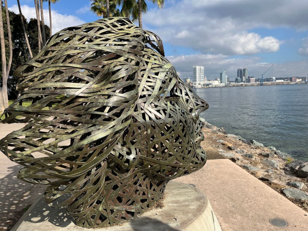 Metal sculpture overlooking the waterfront in Coronado, CA, with cityscape view.
