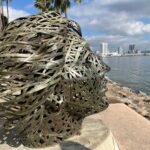 Metal sculpture overlooking the waterfront in Coronado, CA, with cityscape view.
