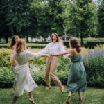 A group of women joyfully dancing in a park on a summer day, exuding happiness.