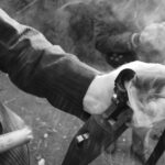 Detailed shot of a hand holding a smoking shotgun, highlighting the action and movement.