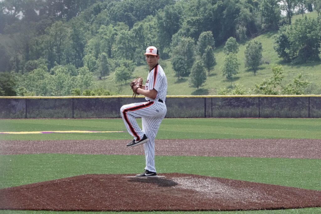 A baseball pitcher prepares to throw on a sunny day at an outdoor field.
