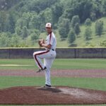 A baseball pitcher prepares to throw on a sunny day at an outdoor field.
