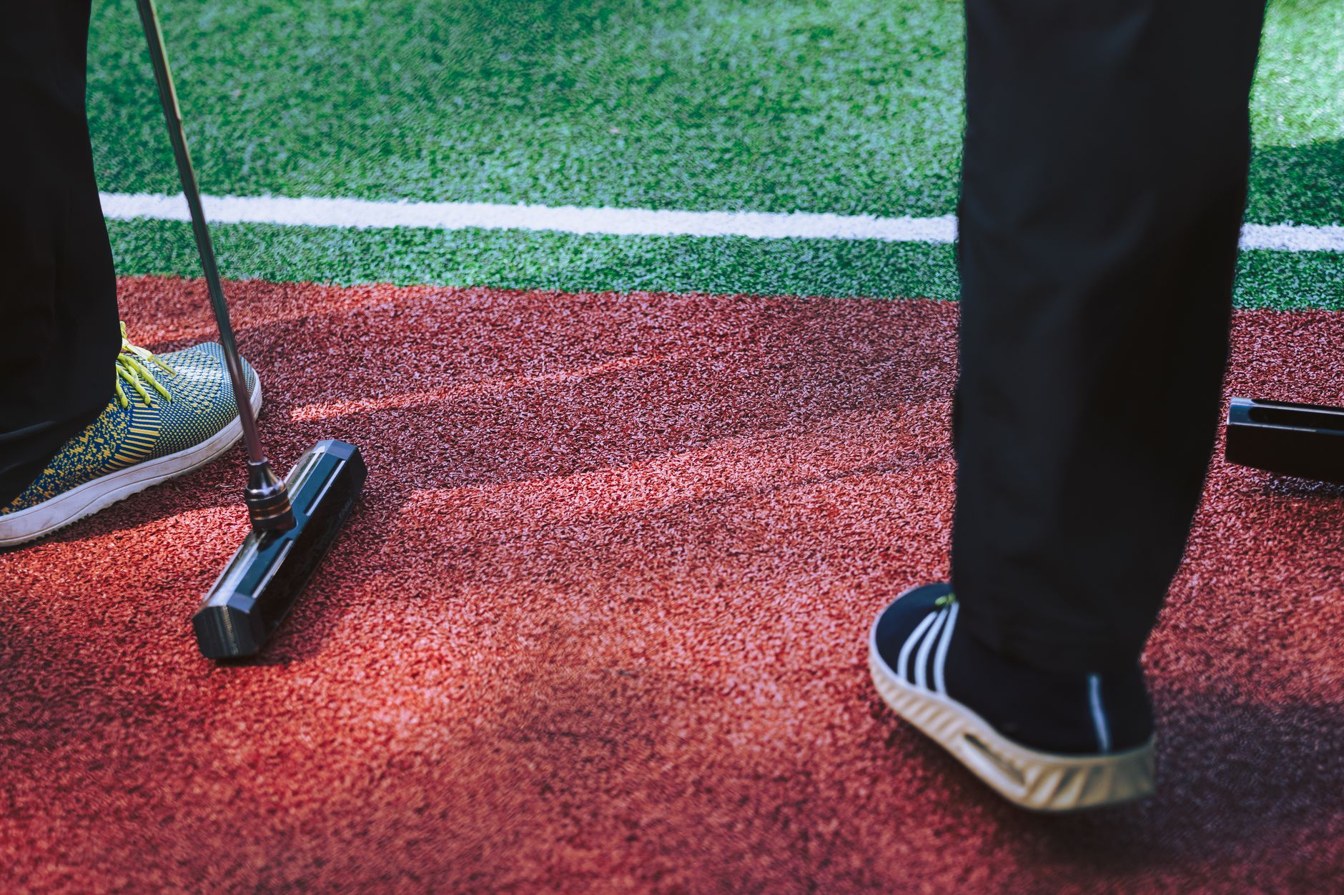 Close-up of players engaging in an outdoor gateball game on a vibrant turf field.