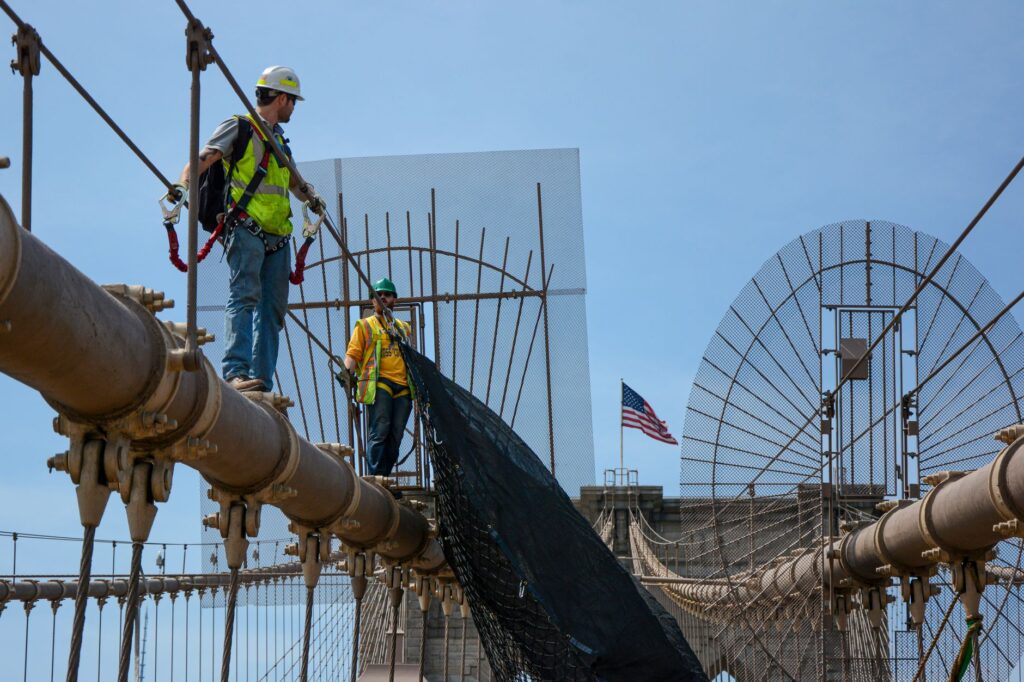 Construction workers performing maintenance on Brooklyn Bridge, NYC.