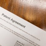 Detailed close-up of a patent agreement document on a polished wooden table.