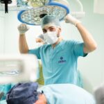 A surgeon in scrubs celebrates after a successful surgery in an operating room.