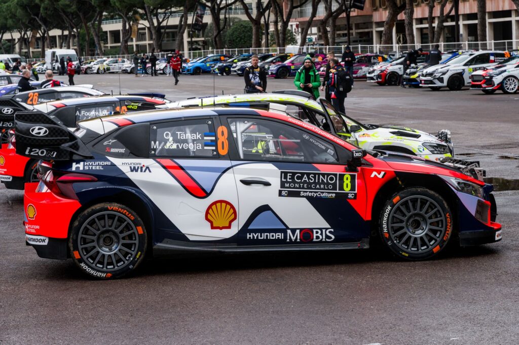 Rally cars lined up in Monaco, showcasing vibrant sponsorship designs.