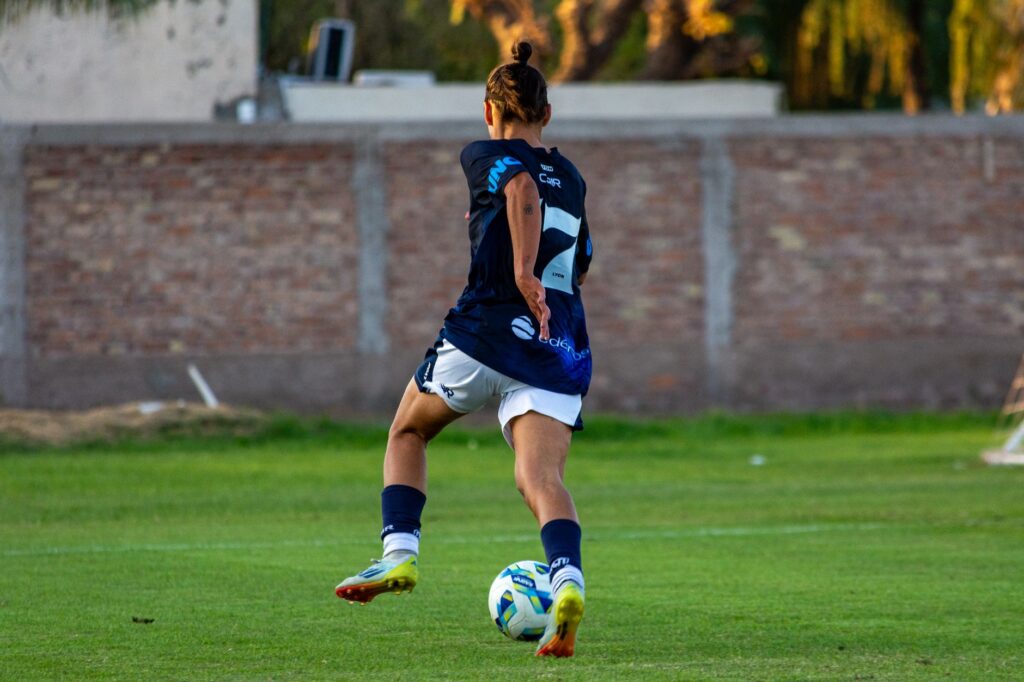 Soccer player in mid-motion on a grassy field, showcasing athletic skill and focus.