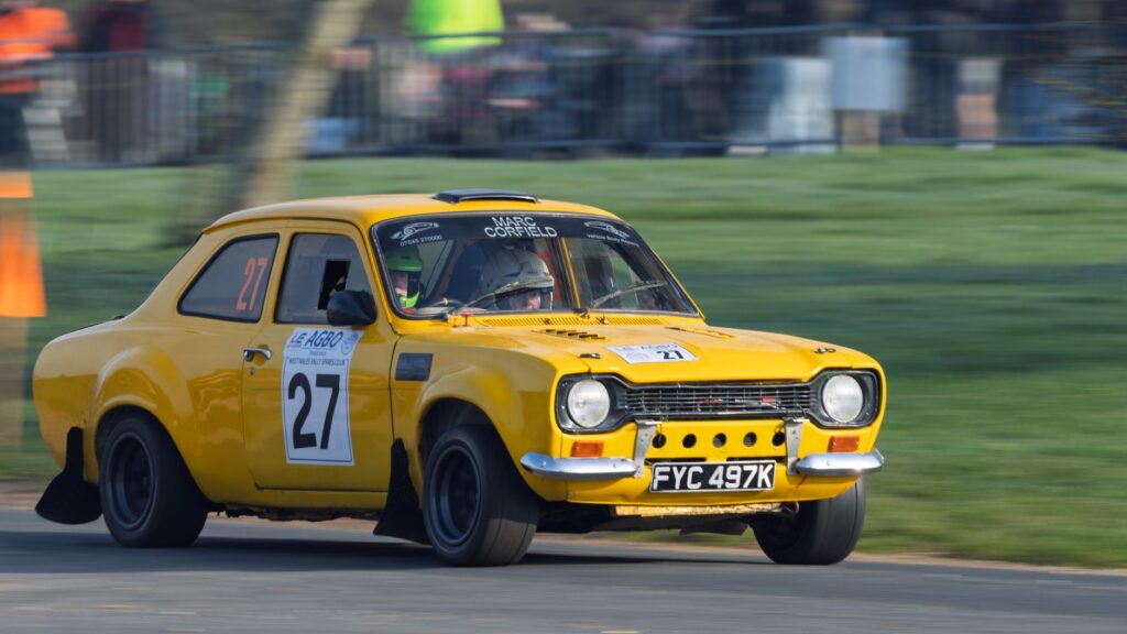 Yellow Ford Escort rally car in action at Weston Park during a motorsport event.