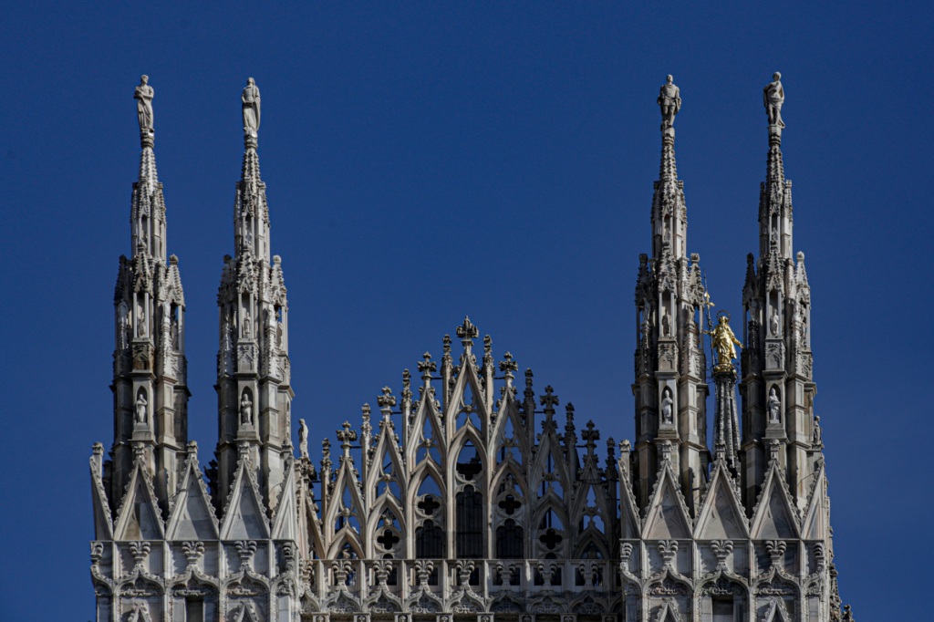 Close-up of the ornate spires of Milan Cathedral against a clear blue sky.