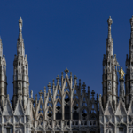 Close-up of the ornate spires of Milan Cathedral against a clear blue sky.
