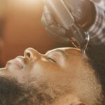 Barber using clippers to trim a client's hair in a bright, relaxed setting.