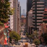 A vibrant view of a San Francisco street leading to the Bay Bridge, showcasing urban architecture and bustling life.