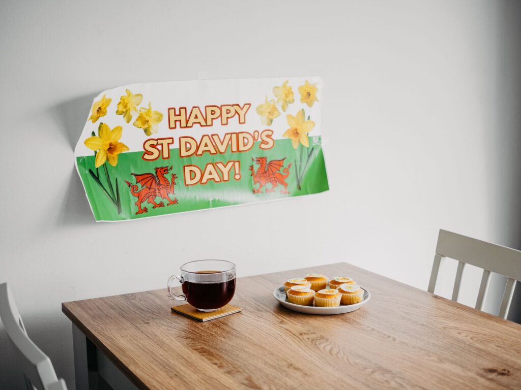 A cozy St. David's Day setup with tea, cupcakes, and festive decor.