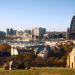 Couple sitting on a hill overlooking Sydney Harbour and the iconic Sydney Harbour Bridge.