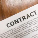 A detailed close-up of a printed contract document on a wooden table surface.