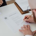 Close-up of a person signing a divorce decree on a desk.