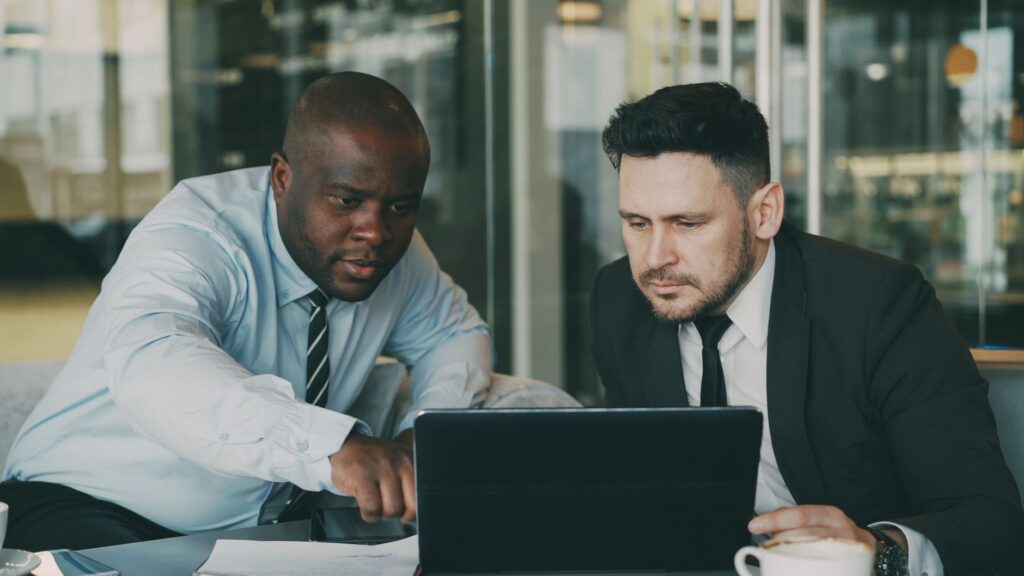 Two businessmen concentrating on a tablet, collaborating in a modern office setting.