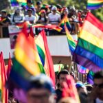 Colorful Pride parade in San Luis Potosí with rainbow flags and a lively crowd.