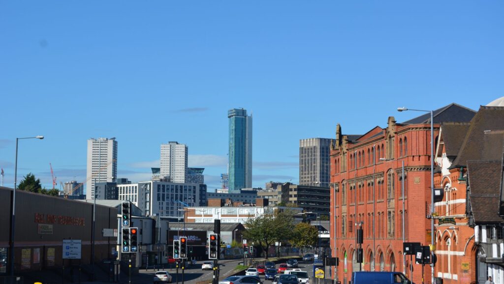 View of a vibrant urban skyline with modern high-rises and historic red brick buildings in England.
