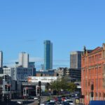 View of a vibrant urban skyline with modern high-rises and historic red brick buildings in England.