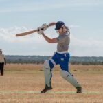 Dynamic cricket scene with a batsman playing confidently on a clear day.