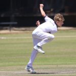 Young cricketer in action on a sunny day, captured mid-bowling with intense focus.