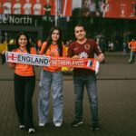 Family posing with England vs Netherlands scarf outside Dortmund stadium for UEFA Euro 2024.