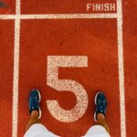 Runner's feet on track lane 5 at the finish line, symbolizing completion and success.