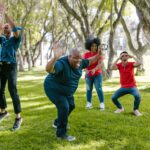 Diverse group enjoying team building games outdoors with joyful expressions.