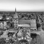 Black and white aerial view of a historic town with a prominent church spire and classic architecture.