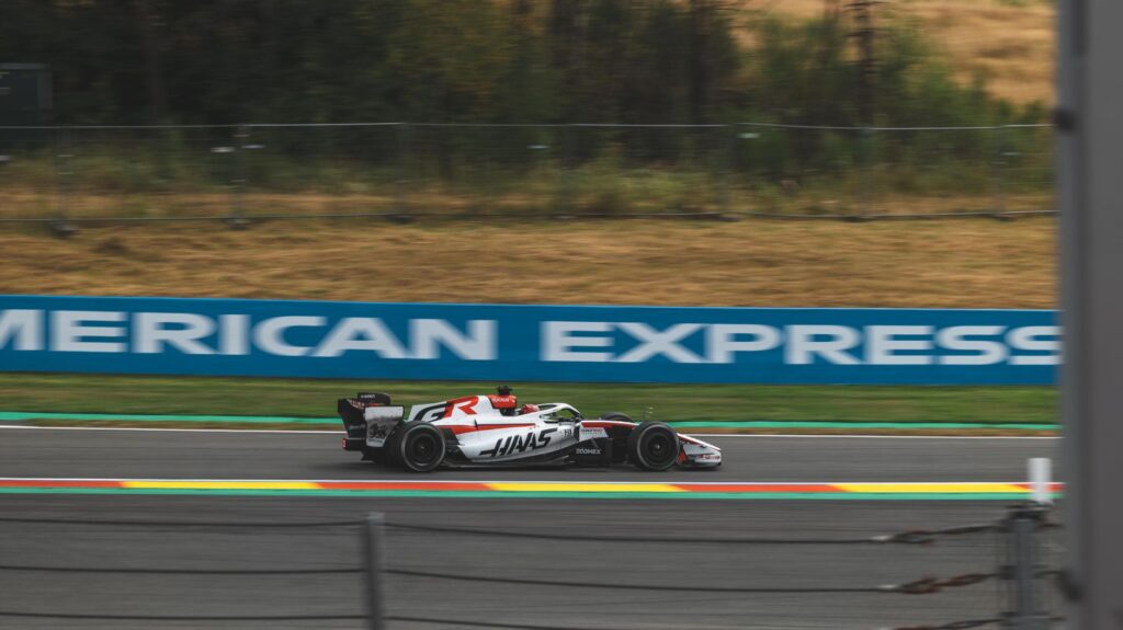 Dynamic shot of a Haas F1 car racing on a track at Spa-Francorchamps, Belgium.