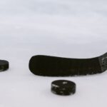 Detailed view of a hockey stick and pucks on ice, perfect for sports visuals.